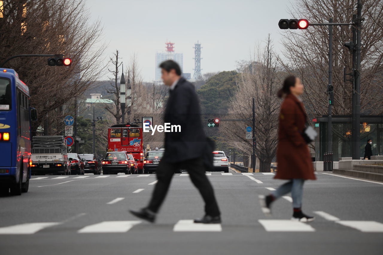 REAR VIEW OF PEOPLE WALKING ON STREET IN CITY