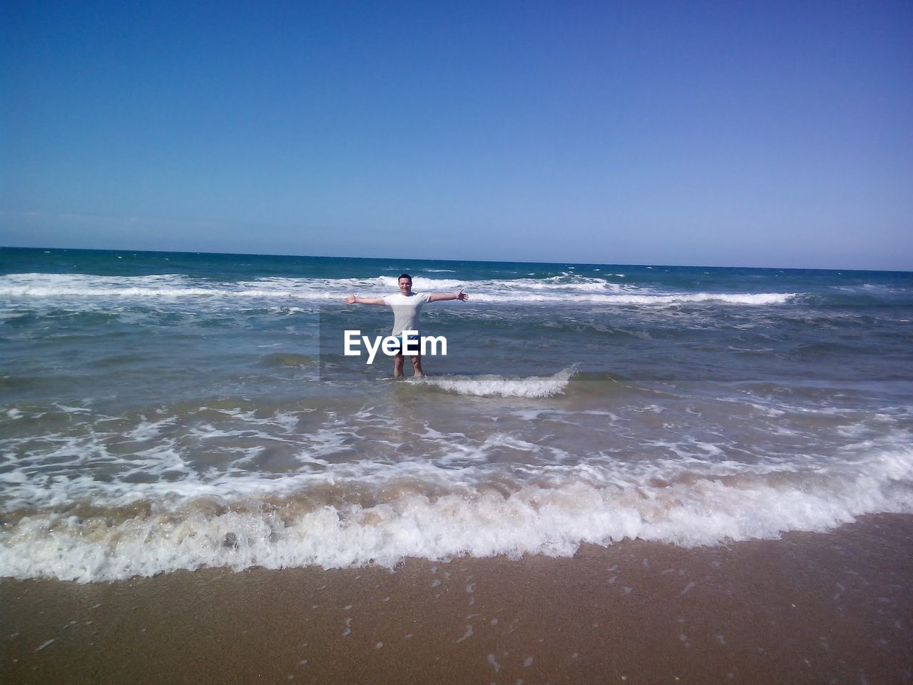 FULL LENGTH REAR VIEW OF MAN AT BEACH AGAINST CLEAR SKY