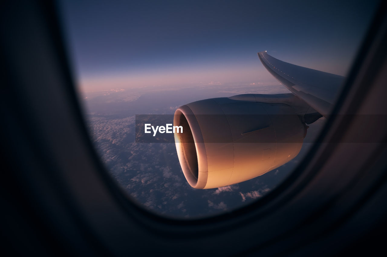 View from window of airplane during night flight above ocean. selective focus on jet engine.