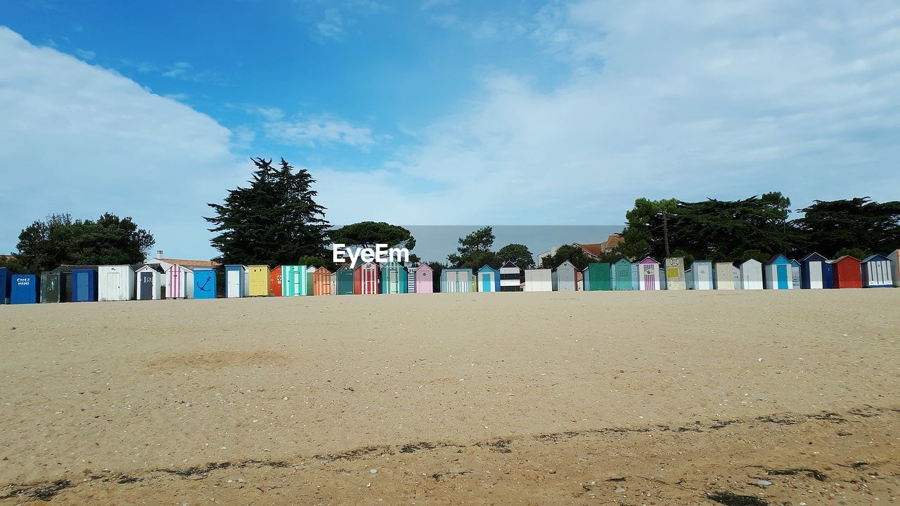 Panoramic view of beach cabins by sea against sky