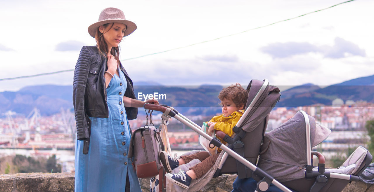 PANORAMIC SHOT OF MAN HOLDING WOMAN AGAINST MOUNTAINS