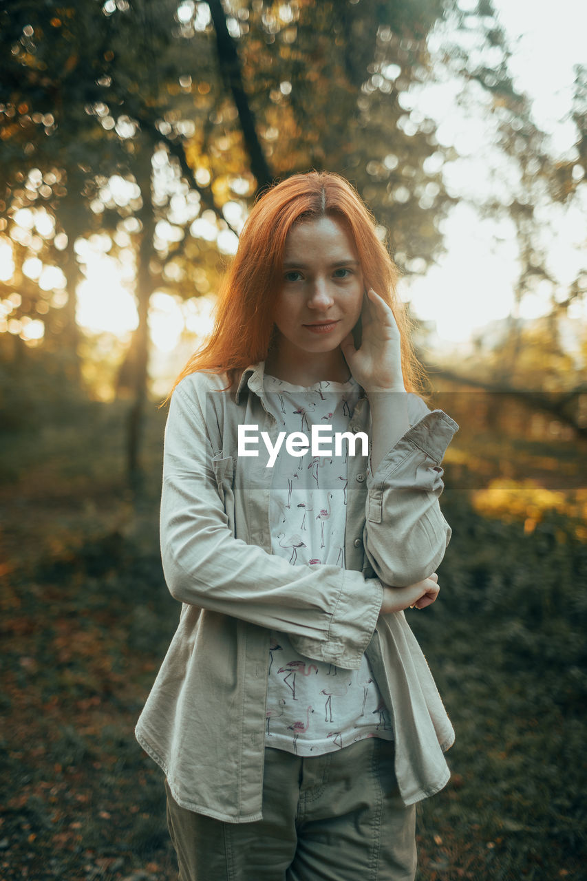 Young woman standing against trees