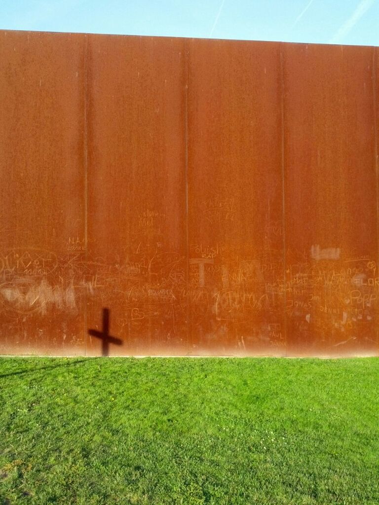 Shadow of a cross on brown wall over grass