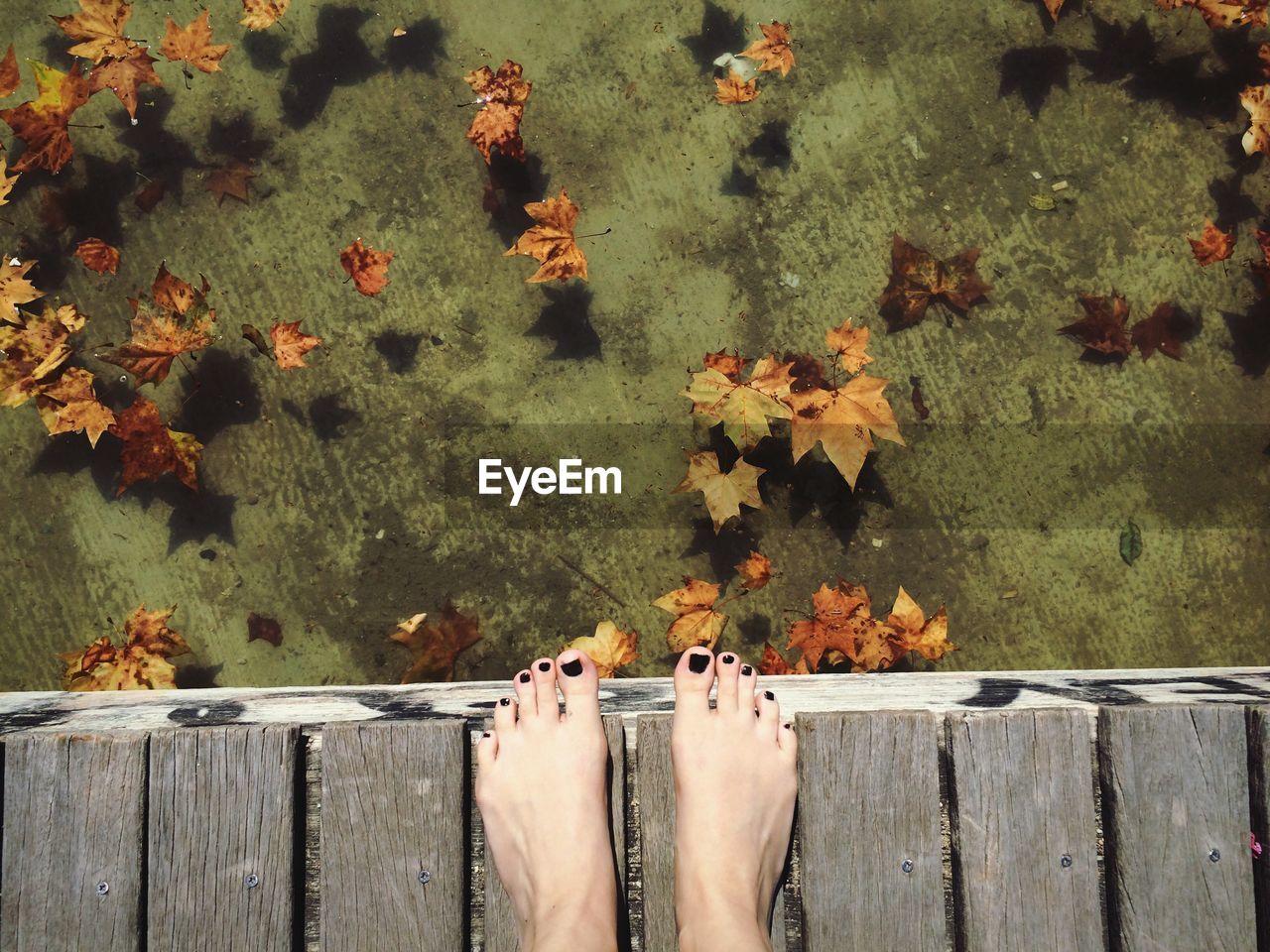 Low section of woman standing on pier over lake