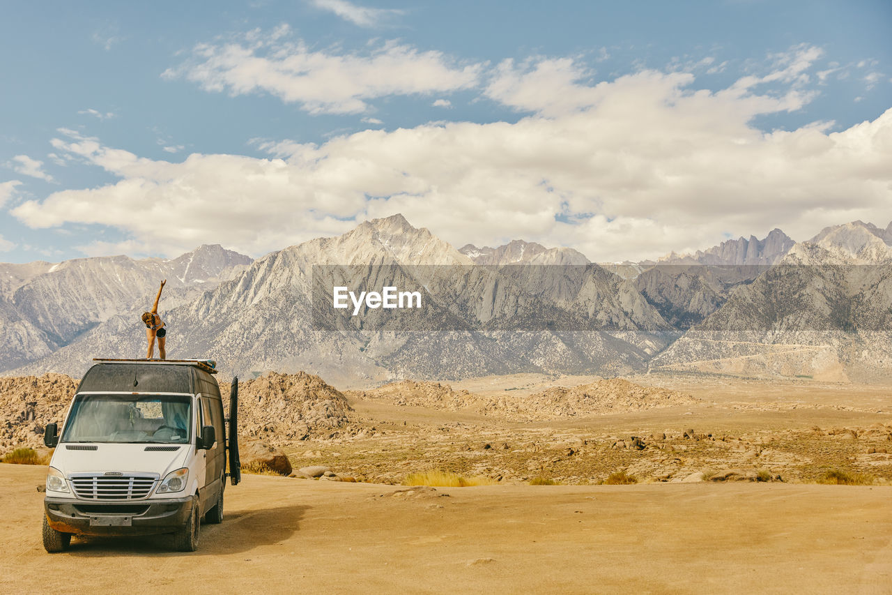 Woman practicing yoga on roof of camper van in northern california.