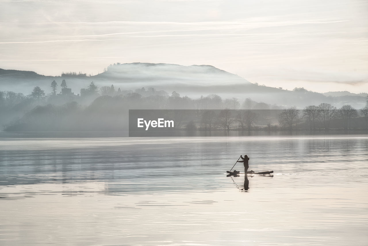 Peaceful paddleboarder on misty lake