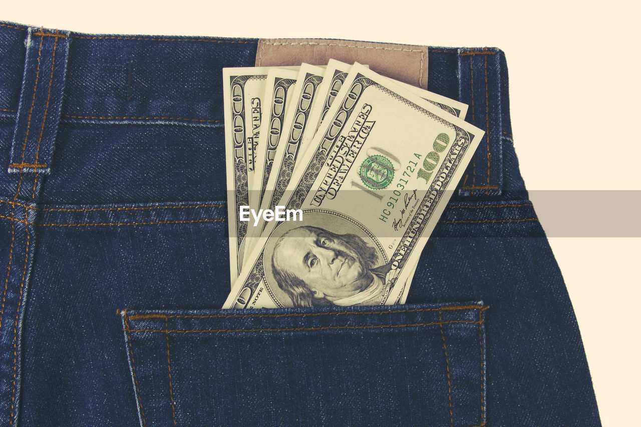 Close-up of paper currency in jeans pocket against white background