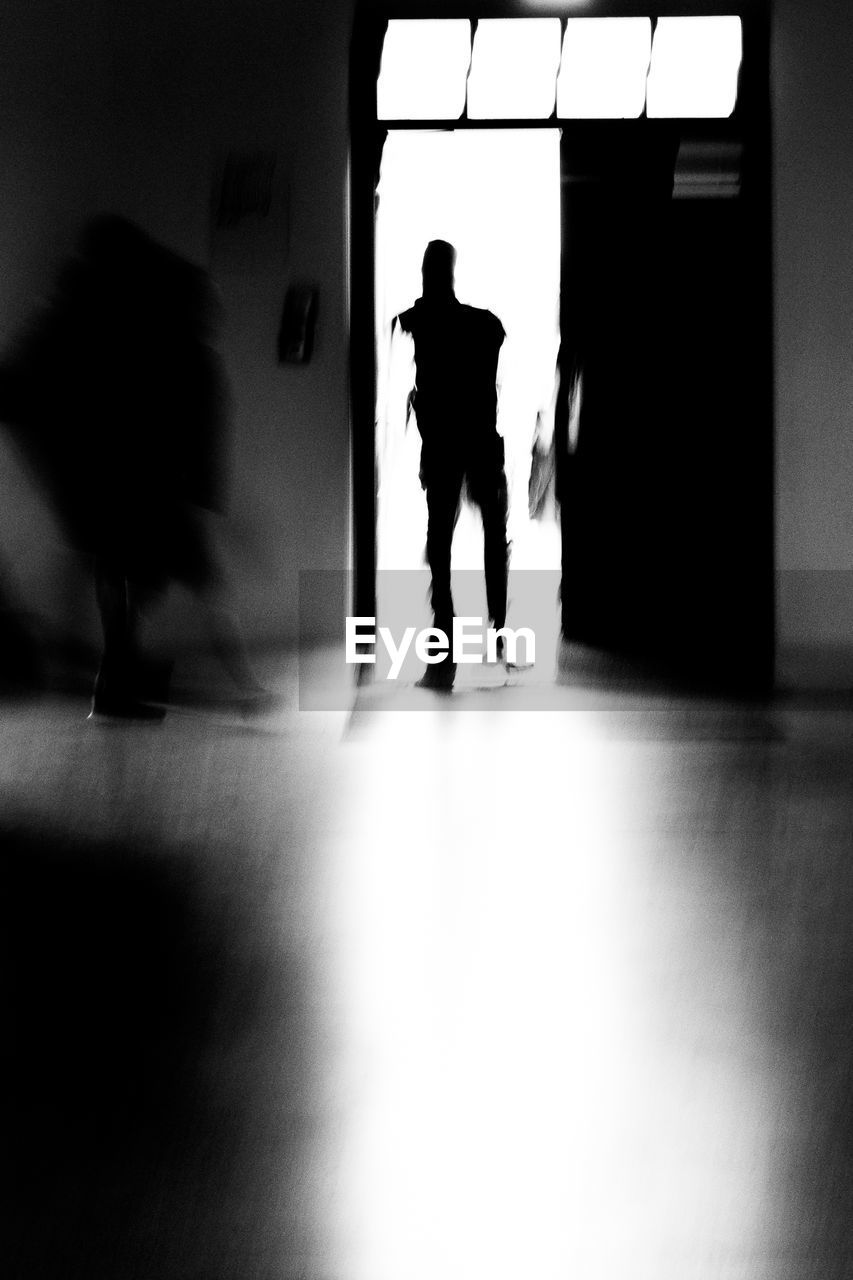 SILHOUETTE OF MAN WITH PEOPLE IN CORRIDOR