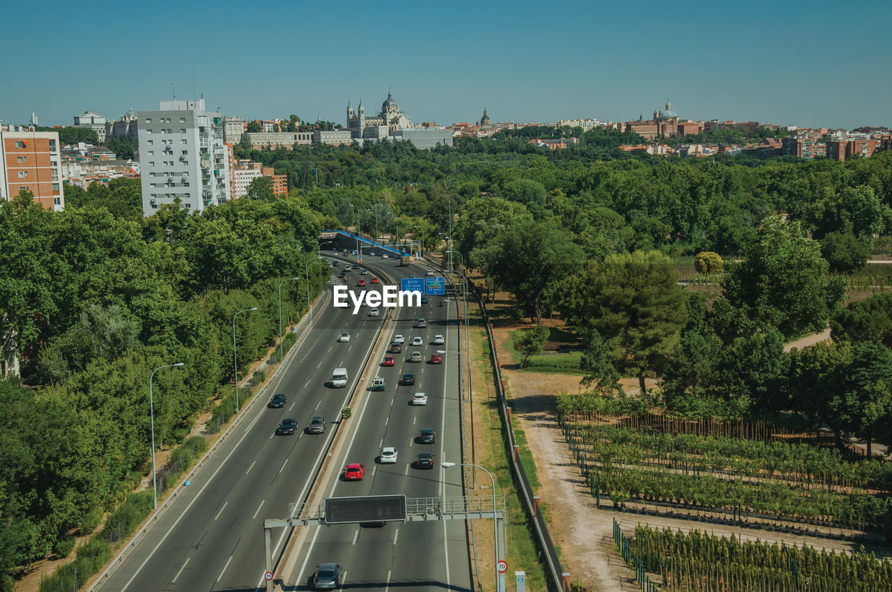 Multi-lane highway with heavy traffic in the midst of trees and buildings in madrid, spain.