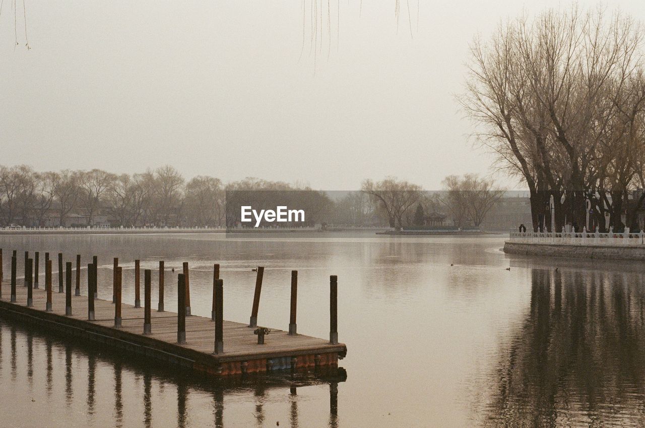 WOODEN POST IN LAKE AGAINST CLEAR SKY