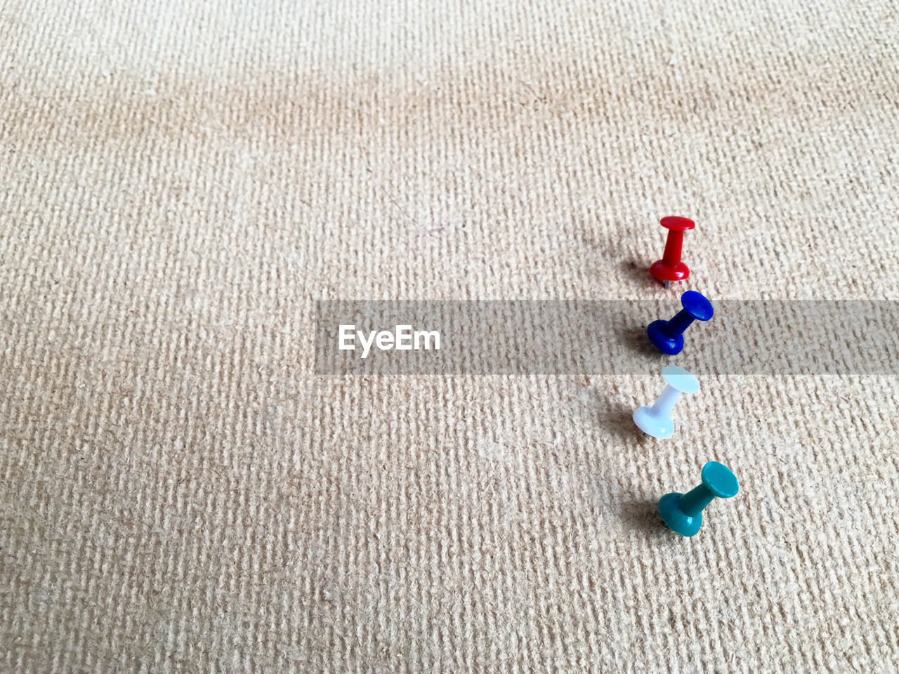 High angle view of colorful thumbtacks on burlap