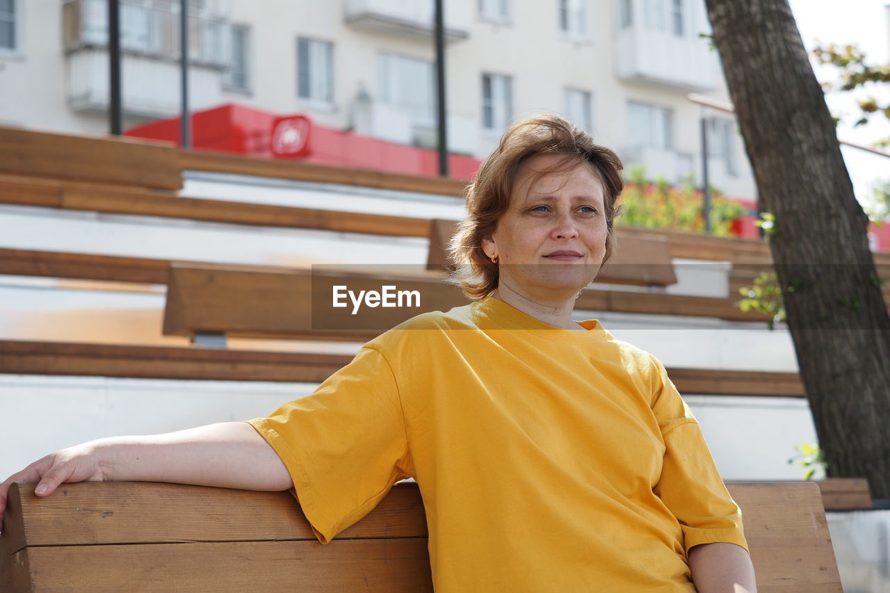 Portrait of a woman. a girl of european appearance on the street in the summer in a yellow t-shirt