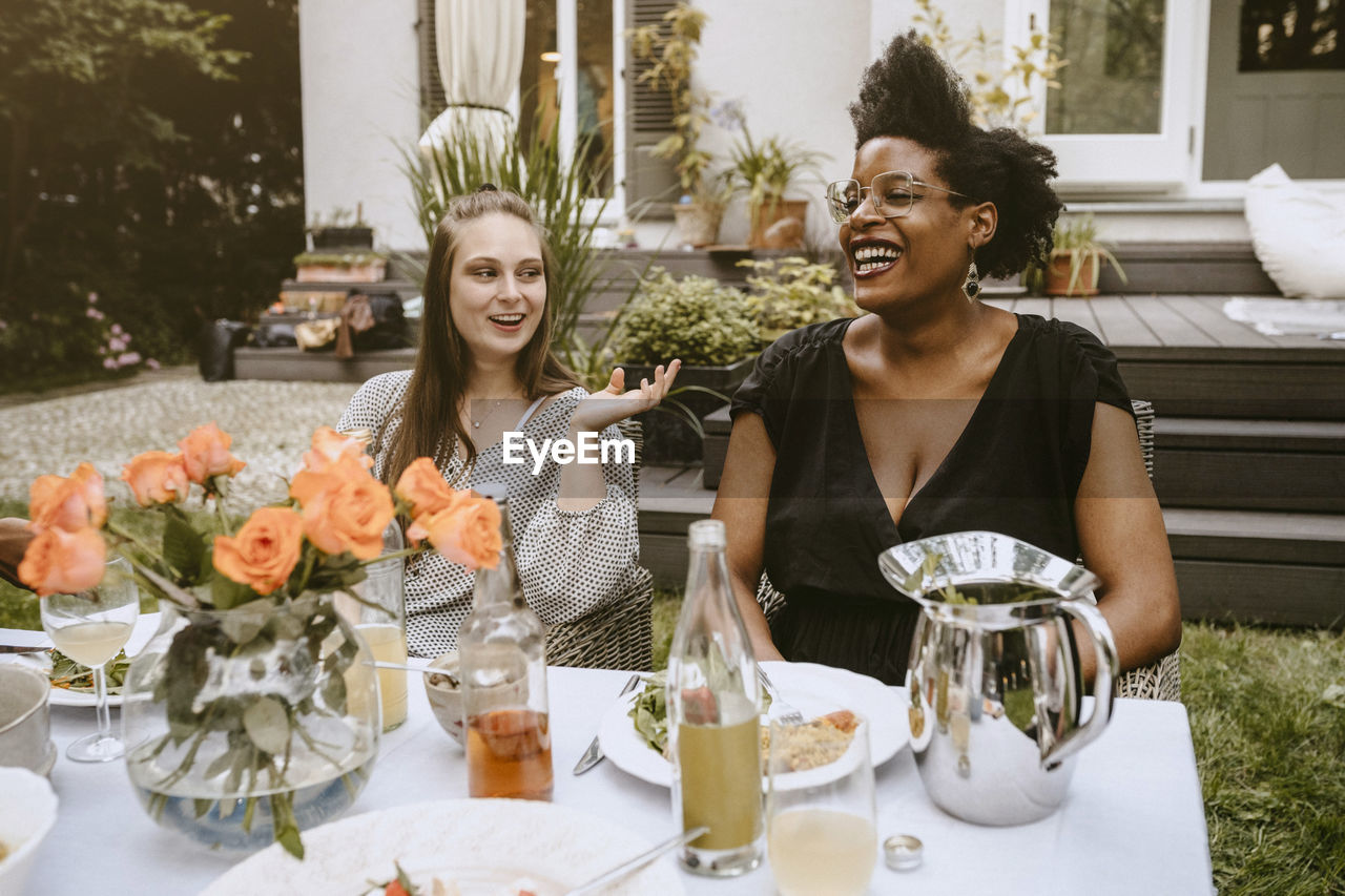Female talking to young friend at table during social gathering