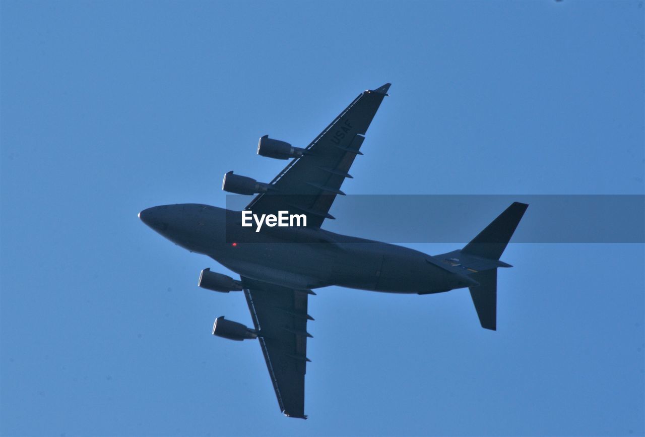 Low angle view of airplane against clear blue sky