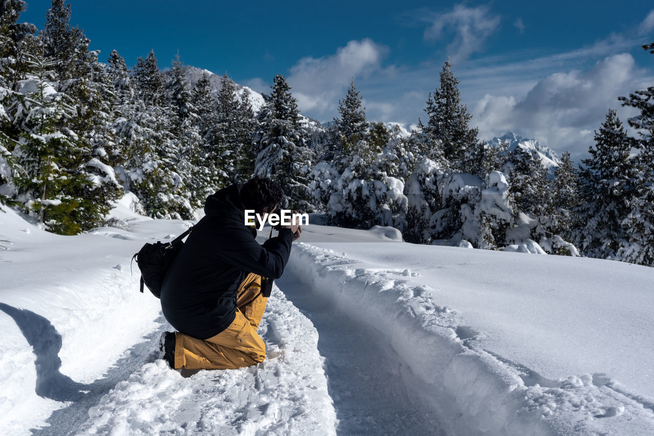 REAR VIEW OF PERSON ON SNOW COVERED MOUNTAINS