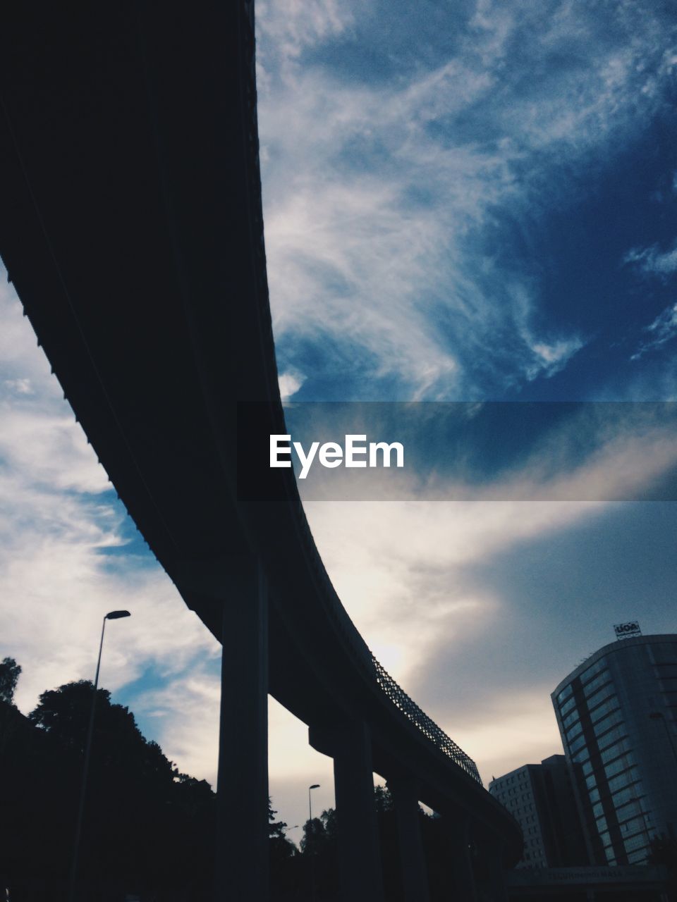 Low angle view of silhouette bridge against sky in city