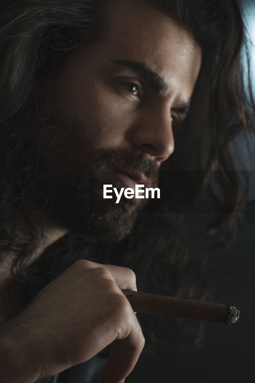 Man holding cigar on black background