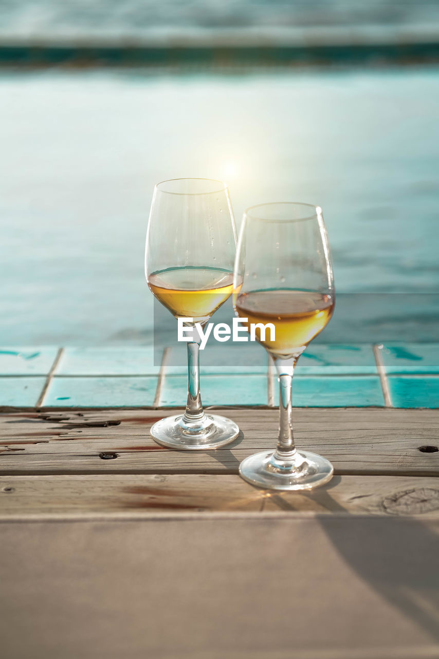 Couple glass of golden sparkling wine oninfinity  pool edge