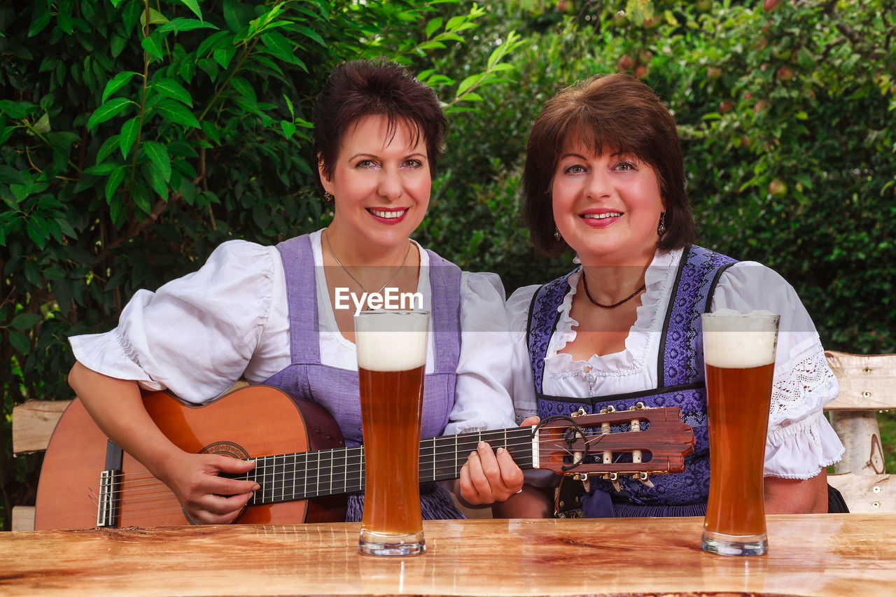 Portrait of smiling women with guitar sitting at table