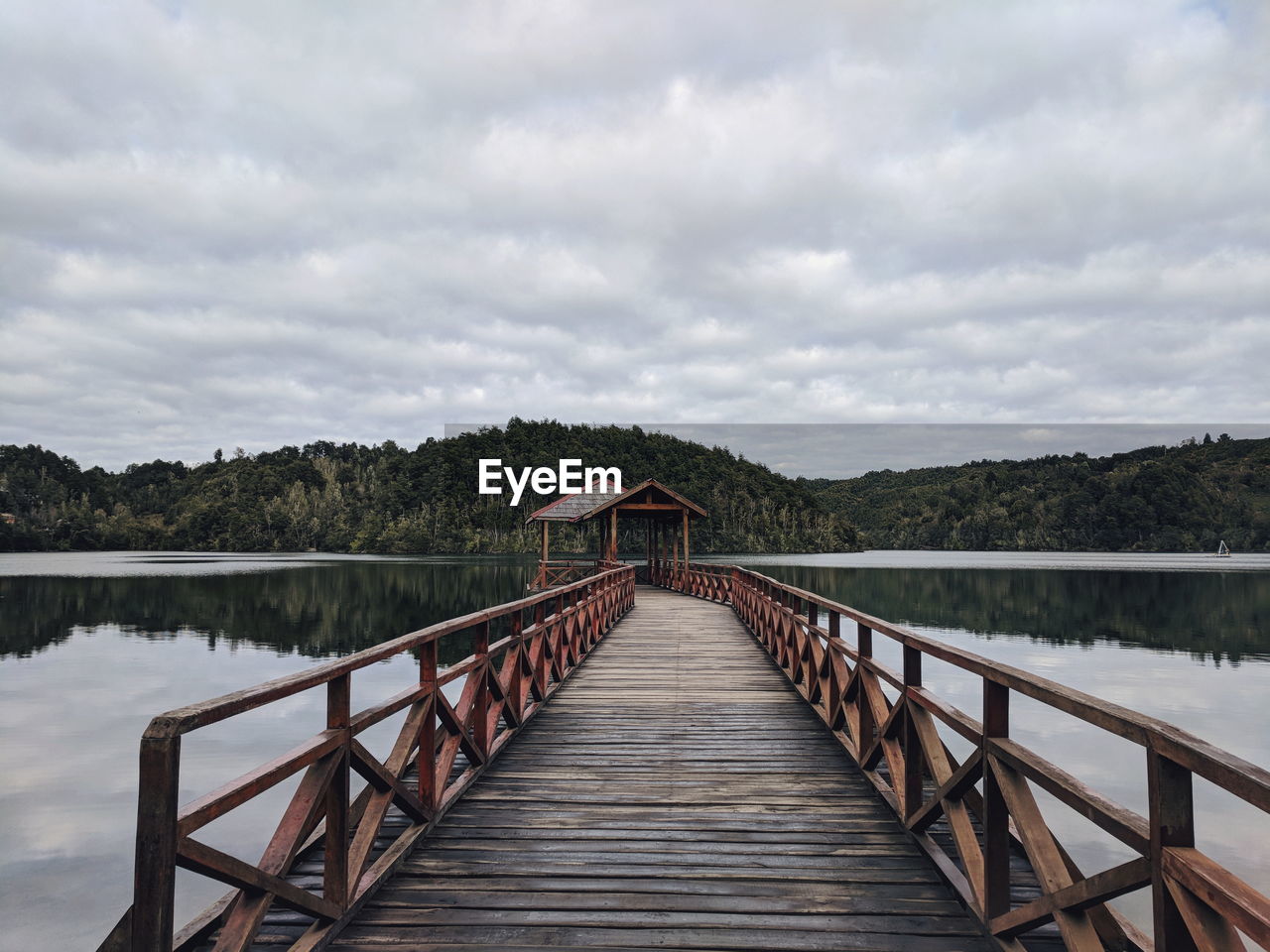 Footbridge over lake against sky