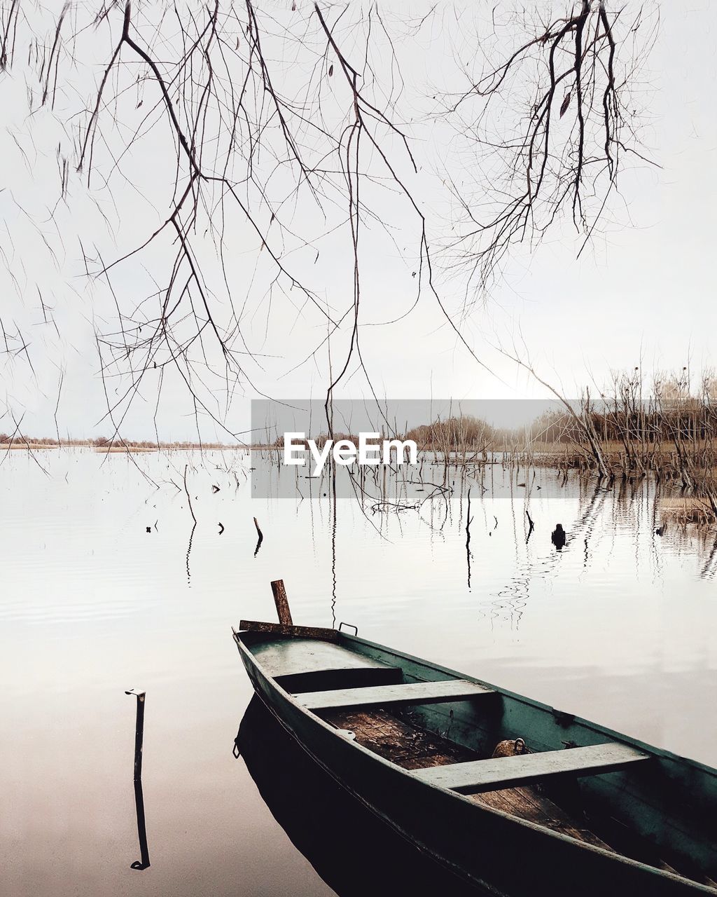 Boat moored at calm lake against clear sky