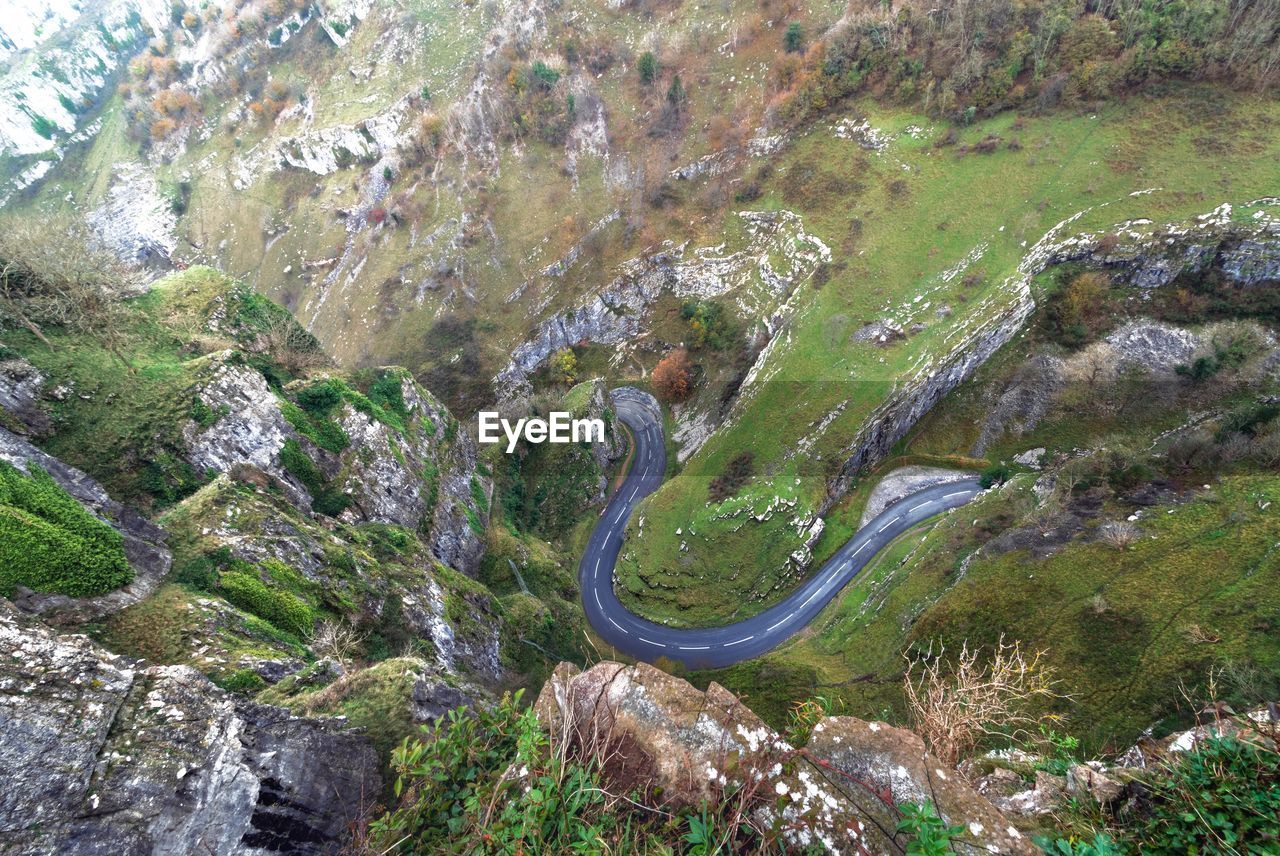 HIGH ANGLE VIEW OF PERSON ON ROCKS BY MOUNTAIN