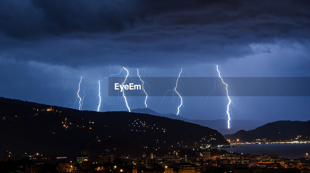 Illuminated cityscape against cloudy sky