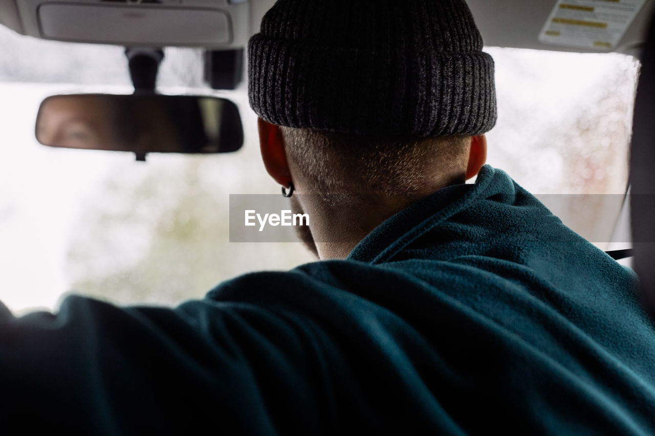 Side view of man wearing knit hat traveling in car