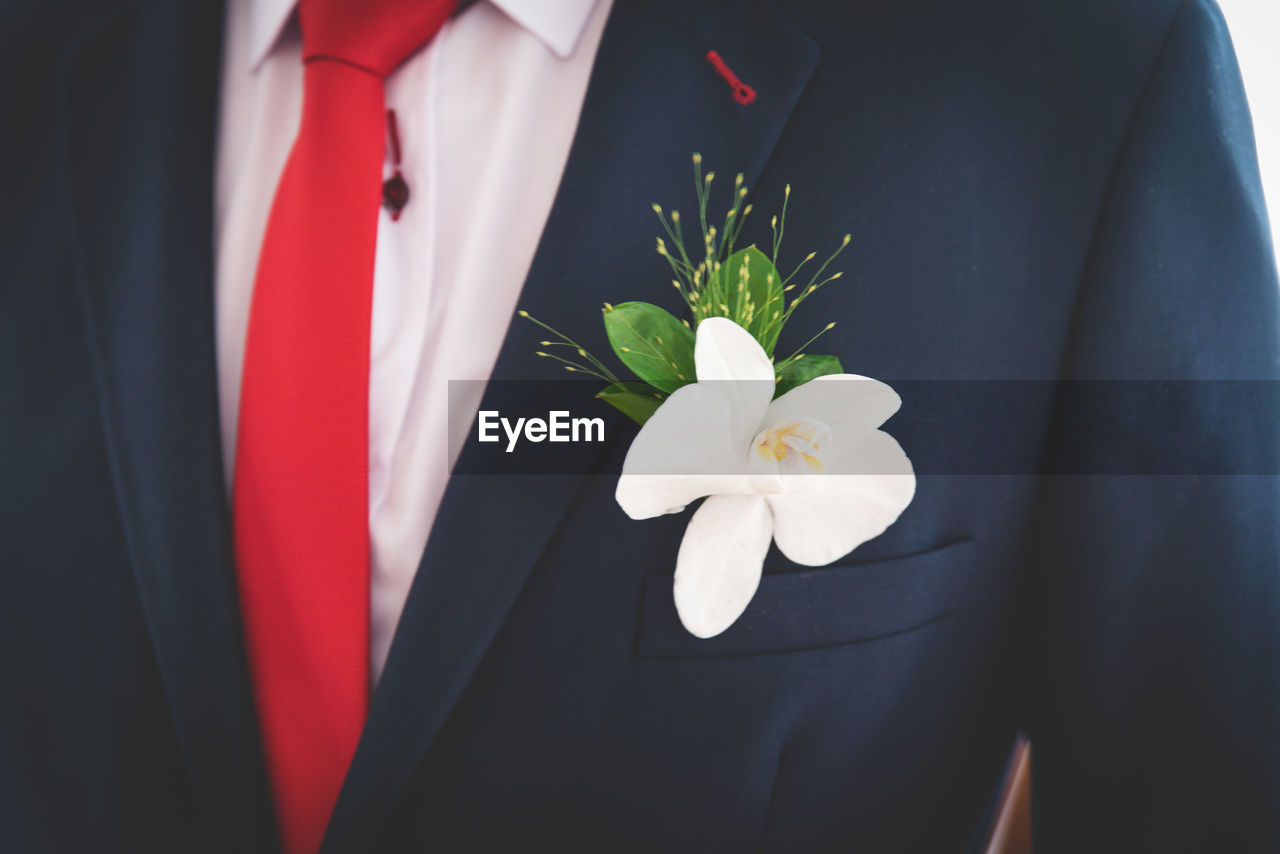 Midsection of bridegroom with flower in pocket