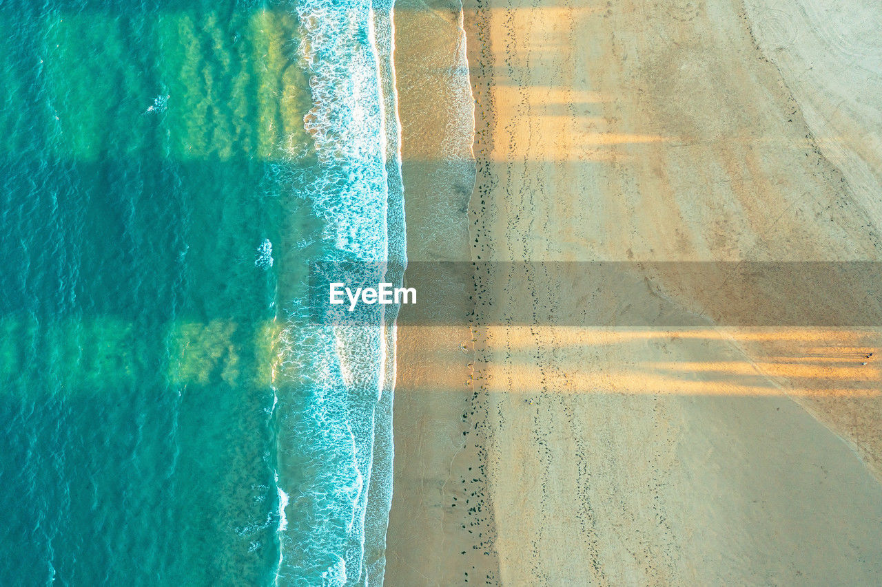 Top view of a sandy beach on the ocean shore. yellow sand, blue water