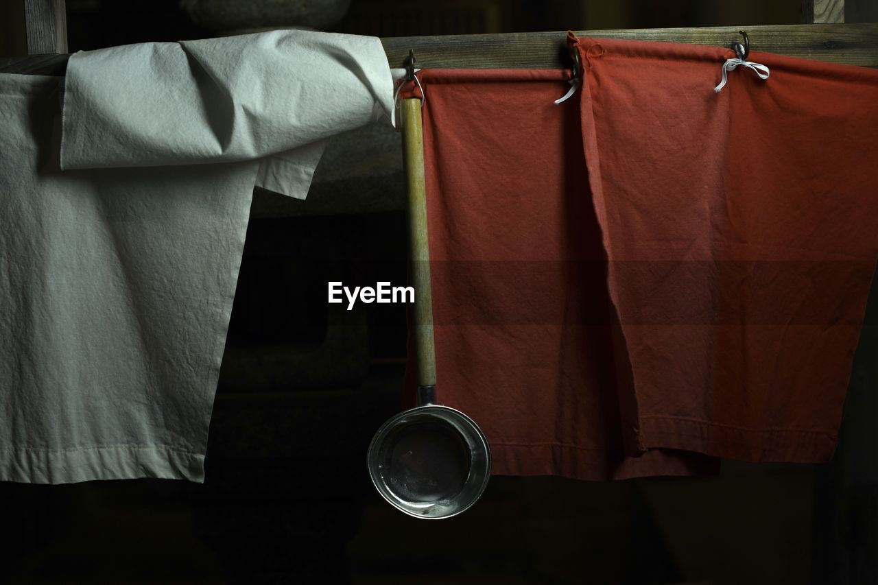 Close-up of kitchen utensil hanging with textile on wall