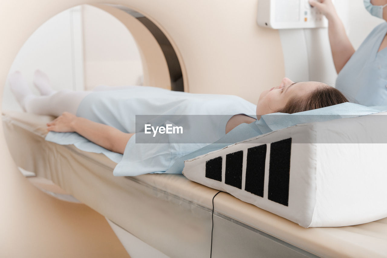 Doctor or nurse and patient with tomography ct or mri scan in hospital. interior of radiography 