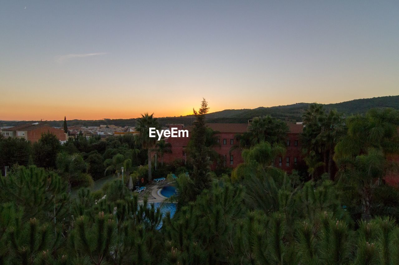 High angle view of trees by house against sky during sunset