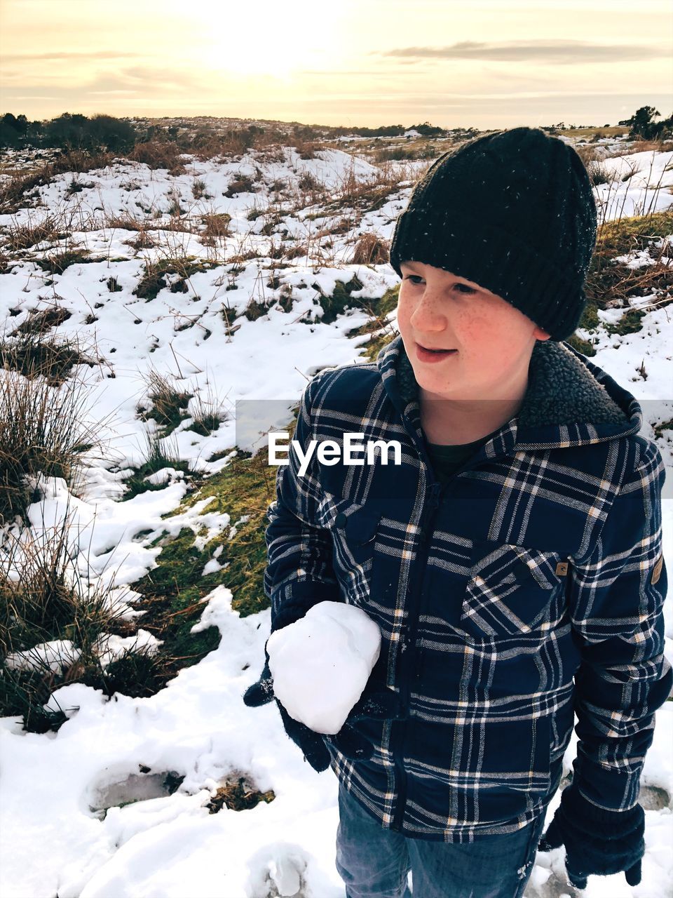 Close-up of boy standing on snow during winter