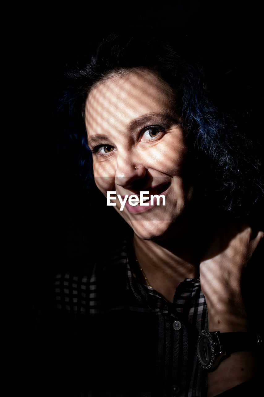 Portrait of smiling woman standing in darkroom