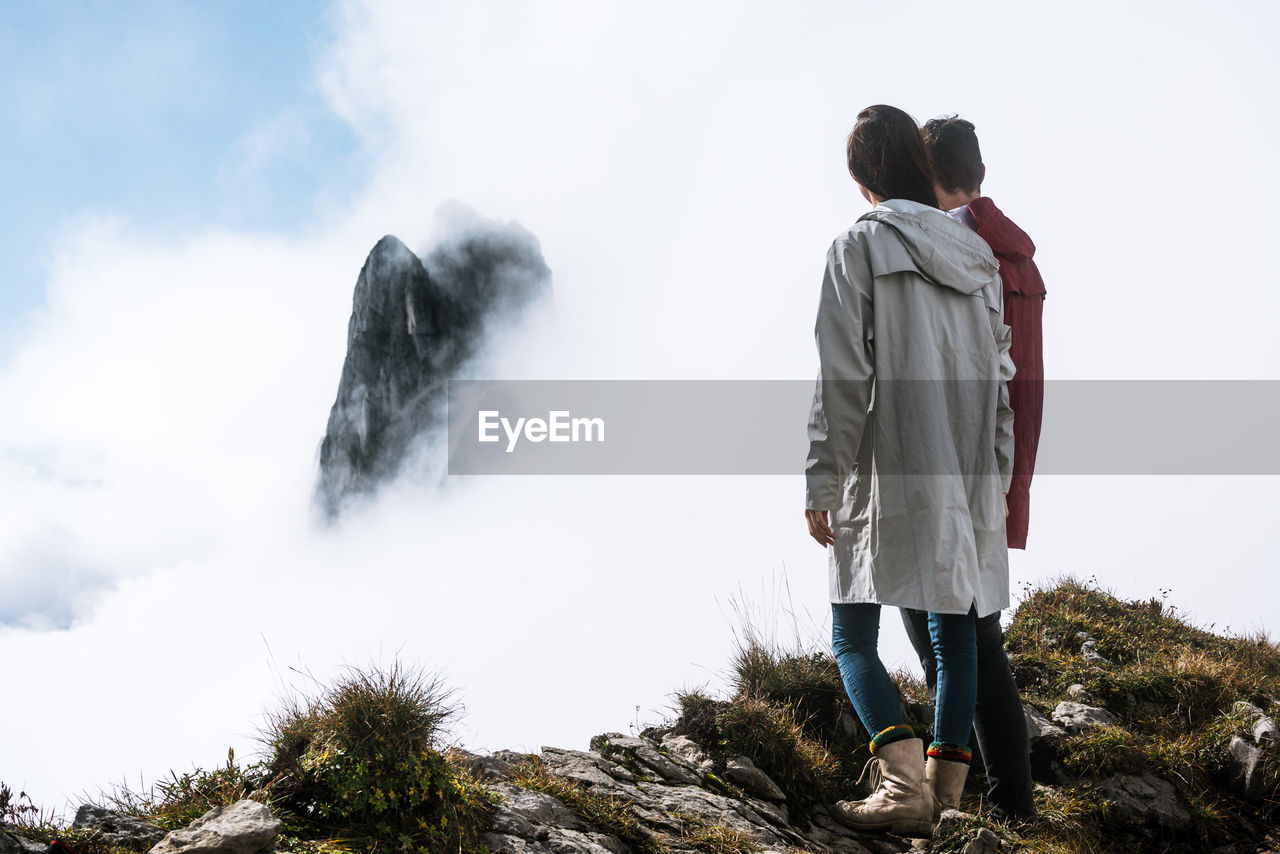 Couple standing against clouds covered mountain