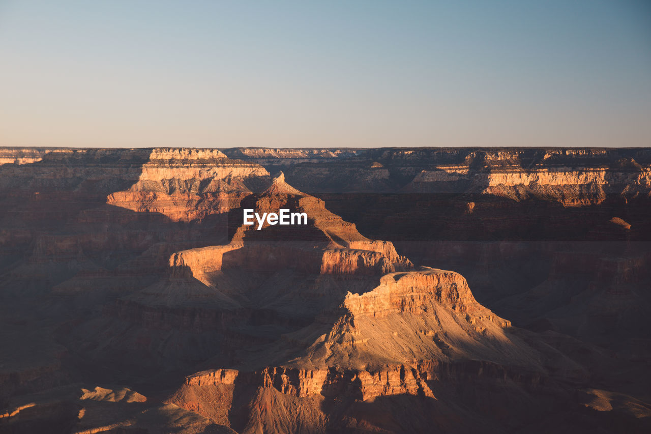 Scenic view of eroded landscape against clear sky during sunset