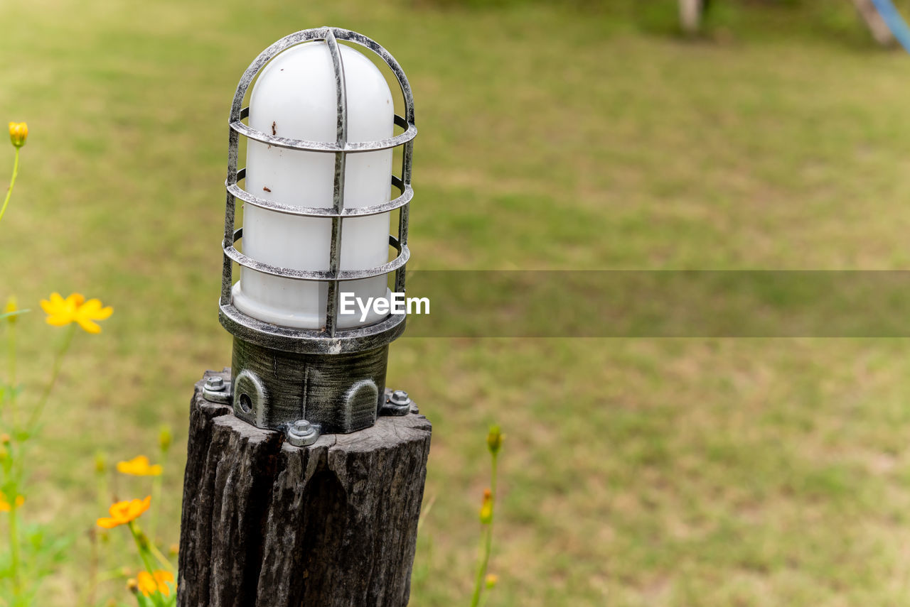 CLOSE-UP OF WOODEN POST ON FIELD BY TREE