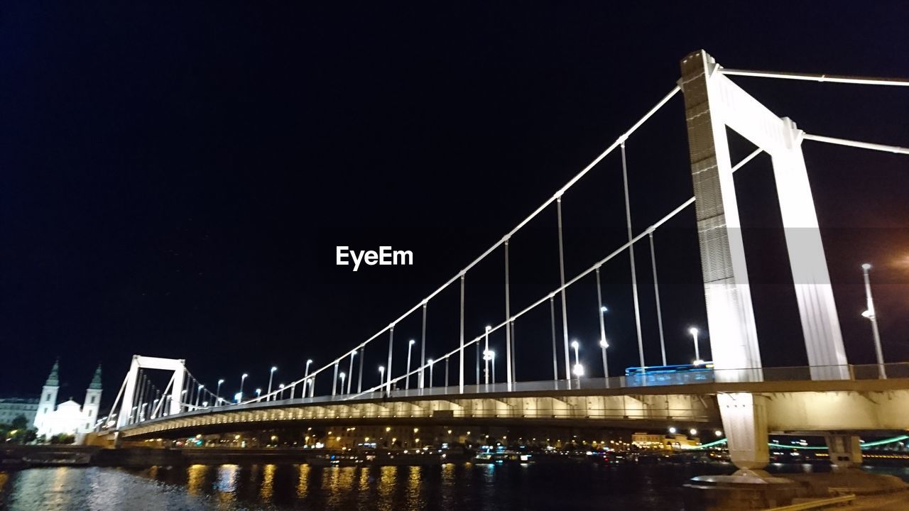 SUSPENSION BRIDGE OVER RIVER AT NIGHT