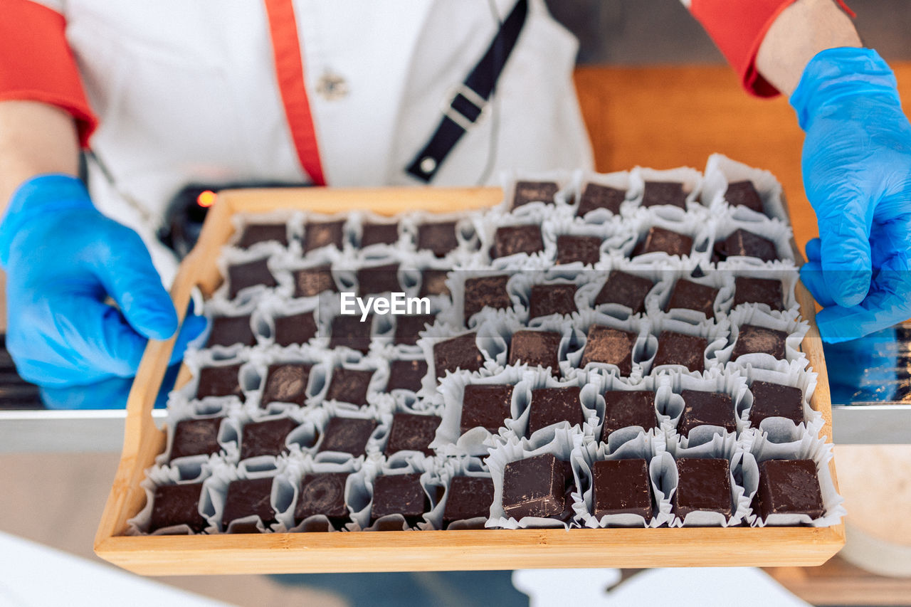 Manufacturin for automatic production of chocolate. worker is holding tray of sweets. sweets modern 