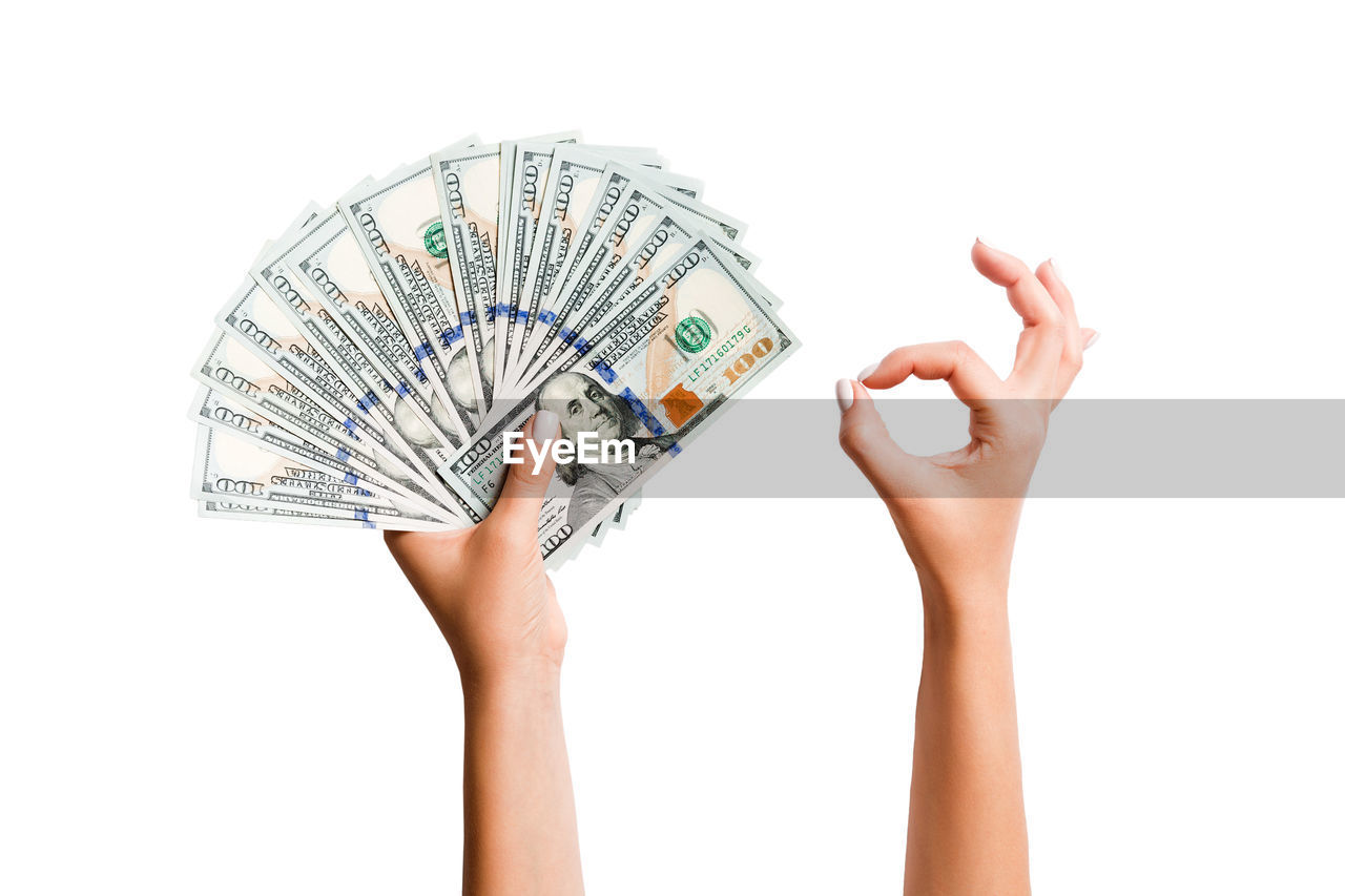 Cropped hands holding paper currencies against white background