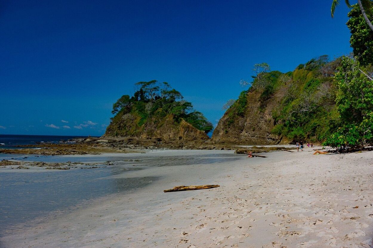 Scenic view of beach against clear blue sky