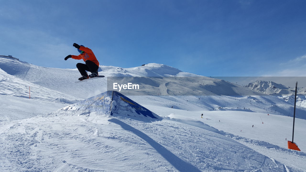 MAN SKIING ON SNOWY MOUNTAIN AGAINST SKY