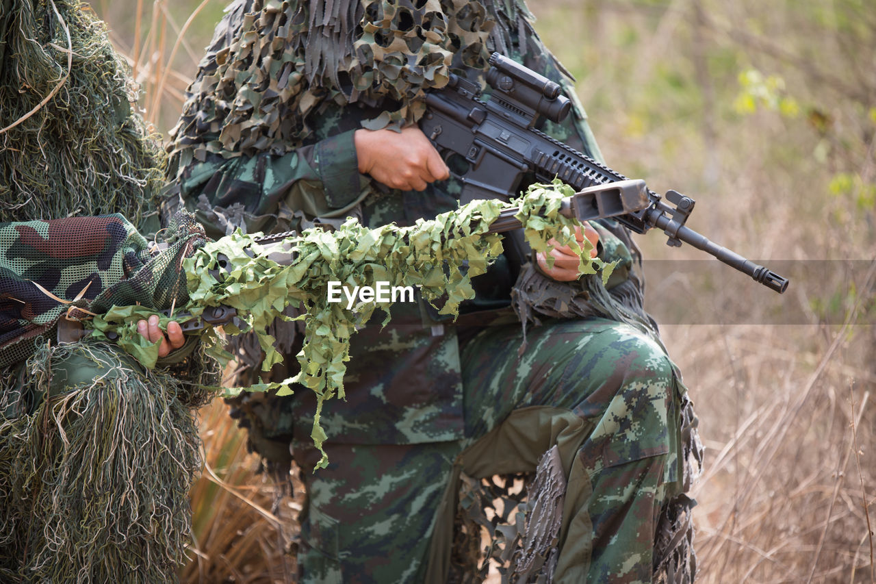 Army soldiers with rifle kneeling in forest