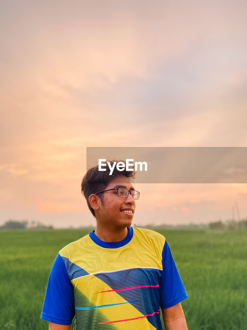 Young man standing against sky during sunset