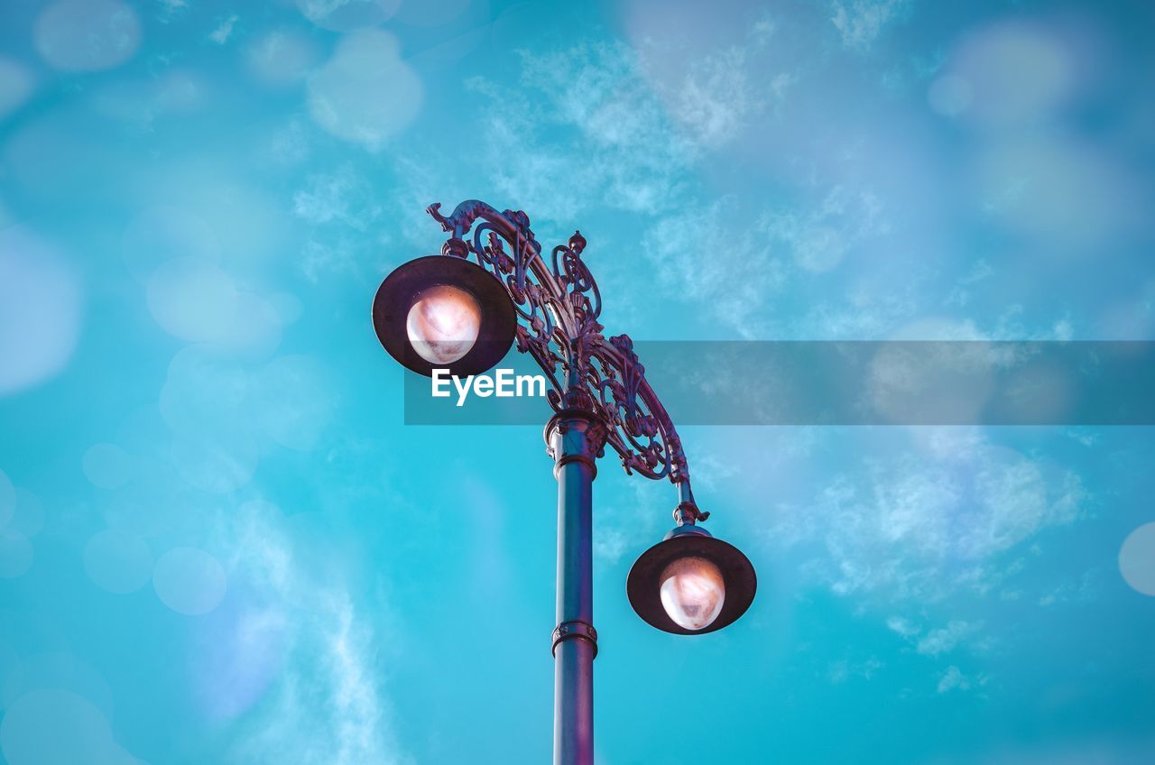 Low angle view of illuminated street light against blue sky