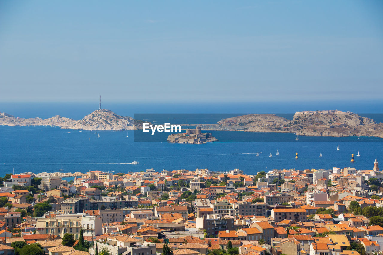architecture, city, building exterior, built structure, sea, water, building, cityscape, horizon, sky, travel destinations, town, nature, coast, residential district, high angle view, travel, land, skyline, no people, aerial photography, tourism, vacation, house, outdoors, blue, day, beach, transportation, scenics - nature, roof, nautical vessel, clear sky, aerial view, city life, harbor, urban skyline, community, horizon over water, landscape, environment, sunny, coastline, mountain