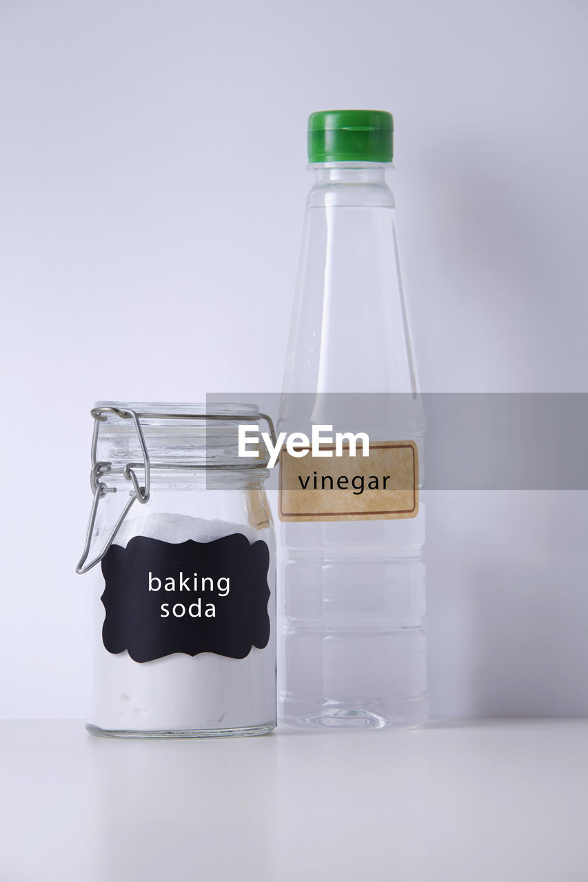 Close-up of baking soda and vinegar on table against white background