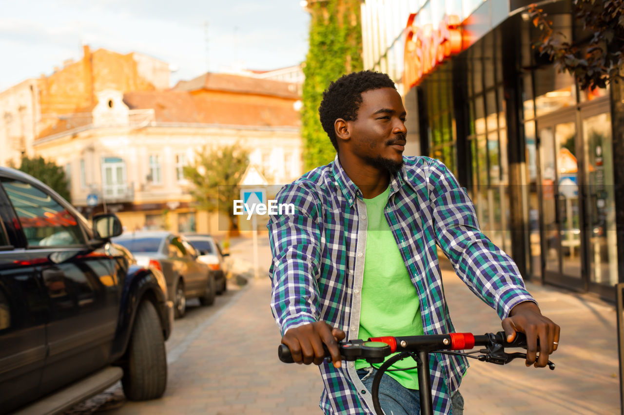 portrait of young man riding bicycle on road in city