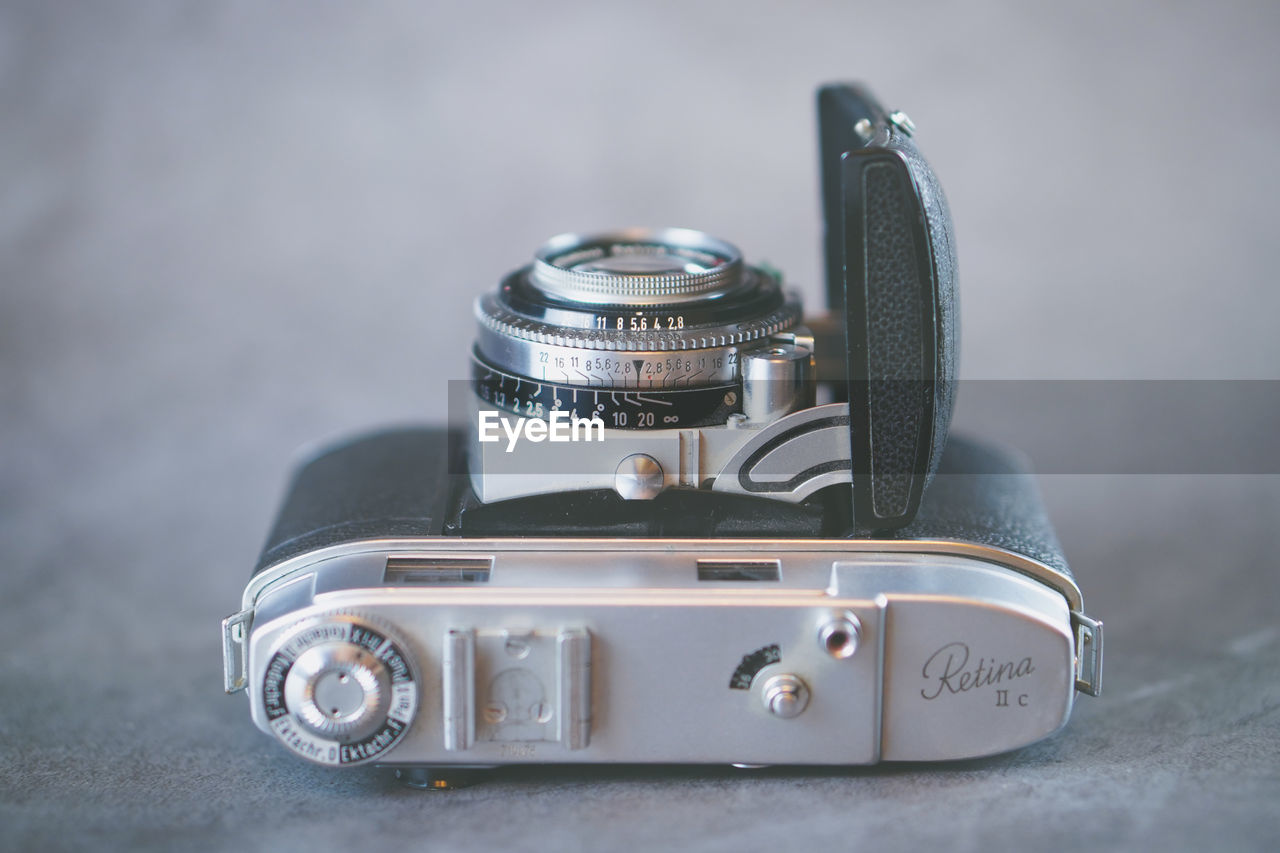 CLOSE-UP OF VINTAGE CAMERA ON TABLE WITH EYEGLASSES